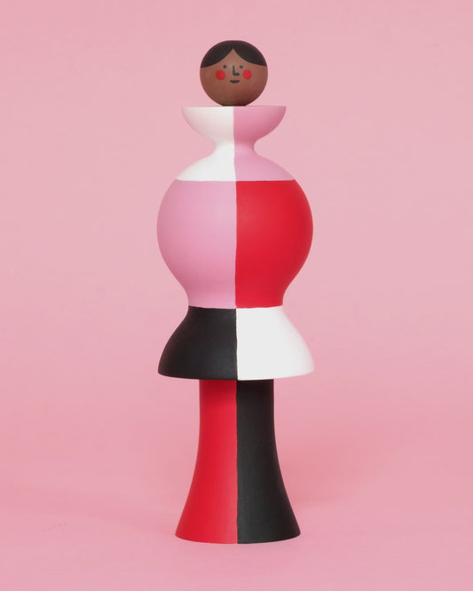 A spinning video of a colourful sculpture with a white, red, black and pink stripey body with red and black legs on a plain pink background.