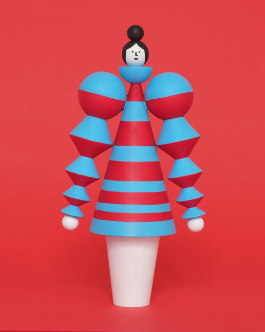 A spinning red and blue wooden figure, featuring a blue and red curved stacked, stripey body with white legs on a plain orange background.