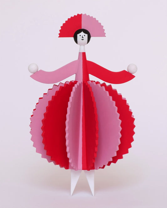 A spinning video of a colourful wooden sculpture with a pink and red stripey 3d round dress and a matching headdress and white legs on a plain white background.