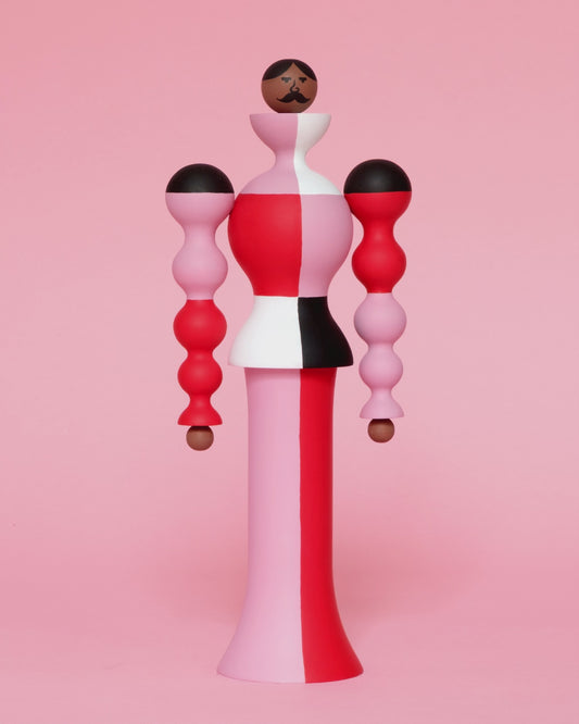 A spinning video of a colourful sculpture with a white, red, black and pink stripey curved body with pink and red legs on a plain pink background.