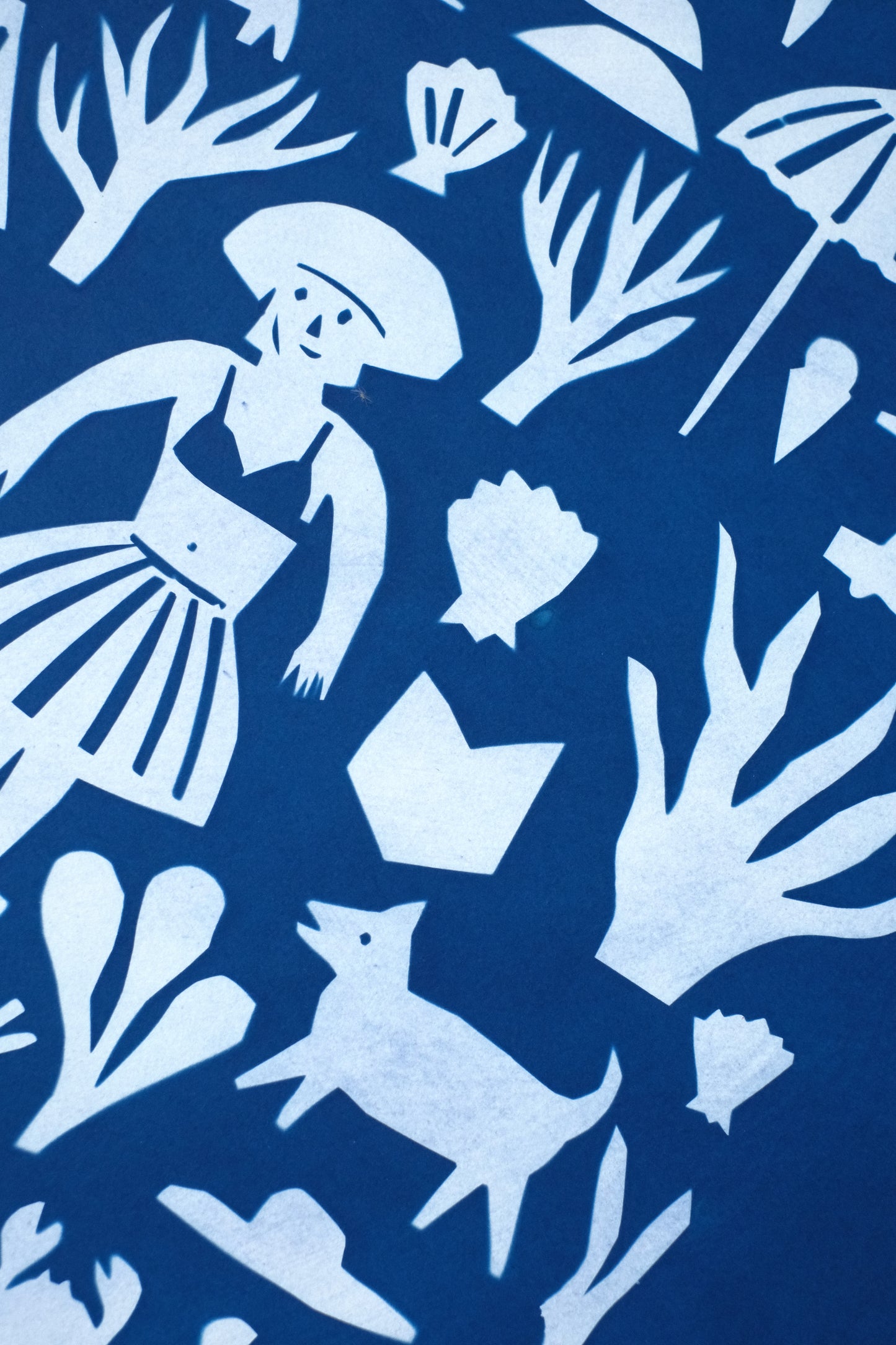 A vibrant blue background features a collage of white silhouettes, including figures, plants, animals, and objects like a boat, umbrella, and bag. The design evokes a playful, whimsical scene, blending elements of nature and everyday life.