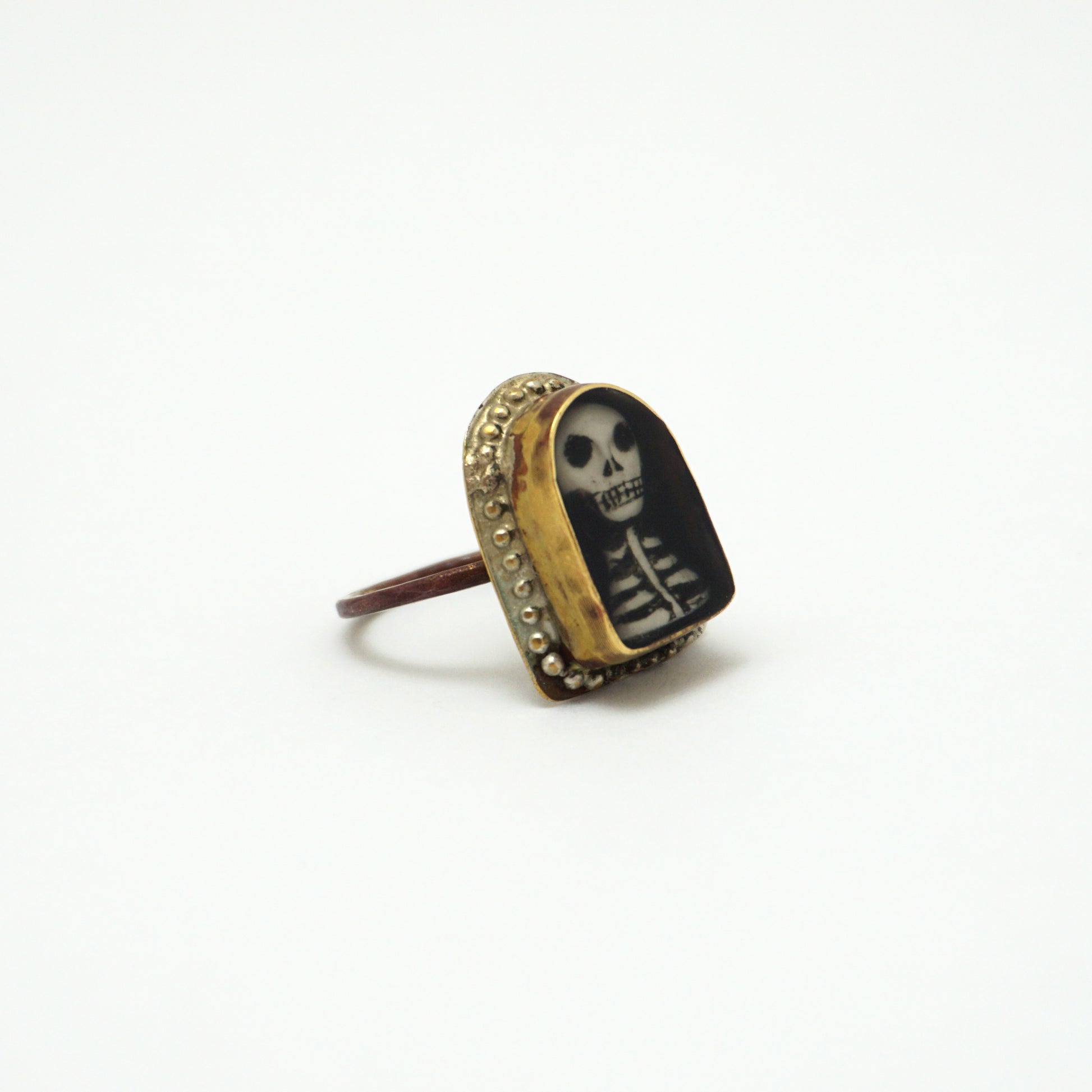 Ring with a hand painted skeleton design in a gold bezel on a white background
