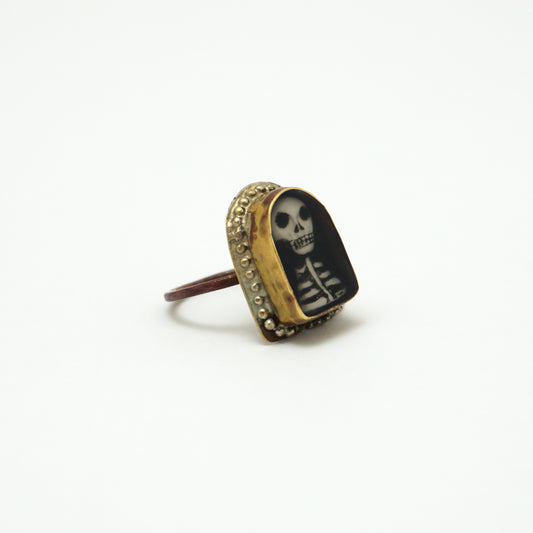 Ring with a hand painted skeleton design in a gold bezel on a white background