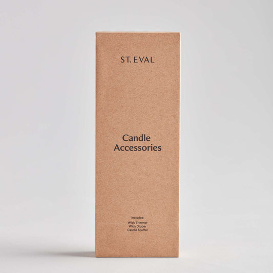 A tall, rectangular cardboard box labelled "Candle Accessories" by St. Eval. The box features a minimalist design with a list of included items: wick trimmer, wick dipper, and candle snuffer, all printed in a simple font.