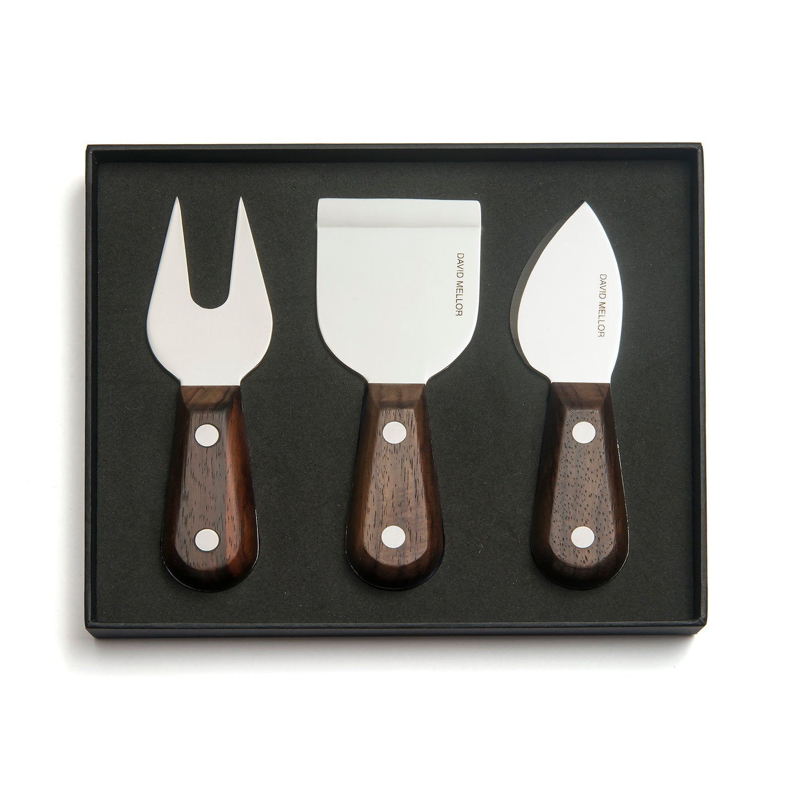 A set of three cheese knives displayed in a black box. The knives feature stainless steel blades and dark wooden handles, including a fork, a flat spatula, and a curved knife, all elegantly designed for serving cheese.