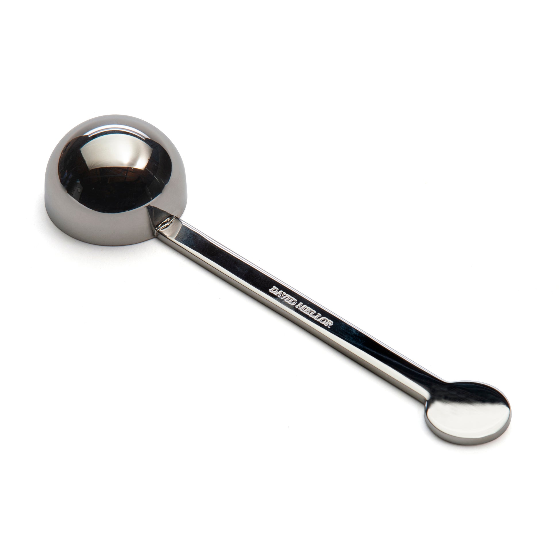 A stainless steel measuring spoon with a round bowl and a long handle, positioned vertically against a plain white background. The spoon has a polished finish, reflecting light subtly.